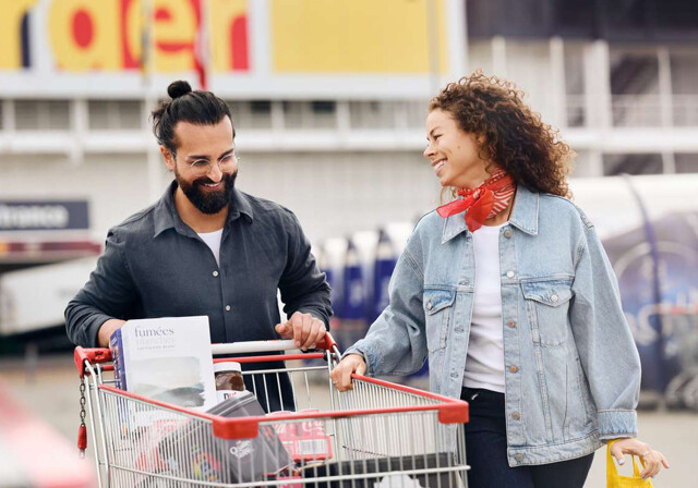 Smilende par foran BorderShop med indkøbsvogn
